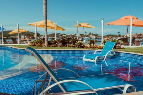 a pool at a resort with chairs and umbrellas at Hotel Paradiso del Sol in Cabo Frio