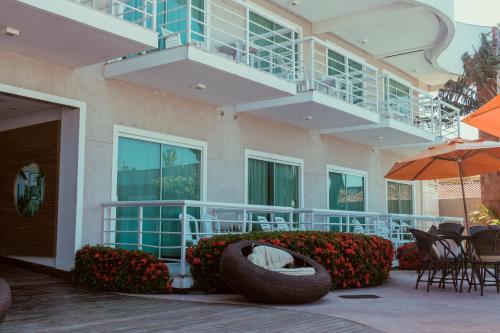 a building with a patio with chairs and an umbrella at Hotel Paradiso del Sol in Cabo Frio