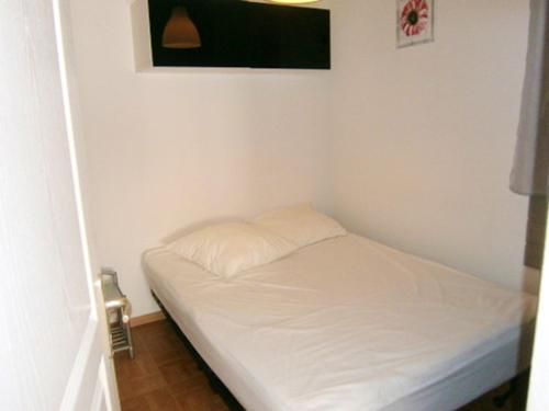 Cette chambre comprend un petit lit blanc et une télévision. dans l'établissement Appartement cosy à Dévoluy avec vue sur la montagne, 26 m²., à Saint-Étienne-en-Dévoluy