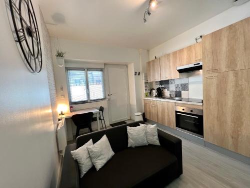 un salon avec un canapé noir et une cuisine dans l'établissement LE CLOS CHASSAING N1 - Wifi - Centre ville-PROPERTY RENTAL NM, à Périgueux