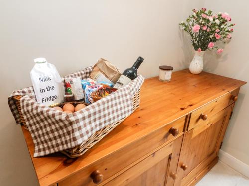 a basket of food and drinks on a wooden dresser at Garth Gill in Sedbergh