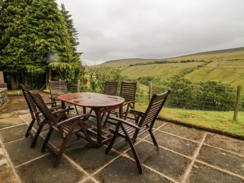 a wooden table and chairs on a patio with a view at Garth Gill in Sedbergh