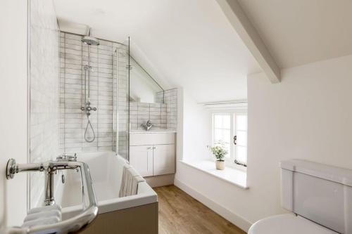 ein weißes Badezimmer mit Badewanne und Waschbecken in der Unterkunft Honeysuckle Cottage in Wareham