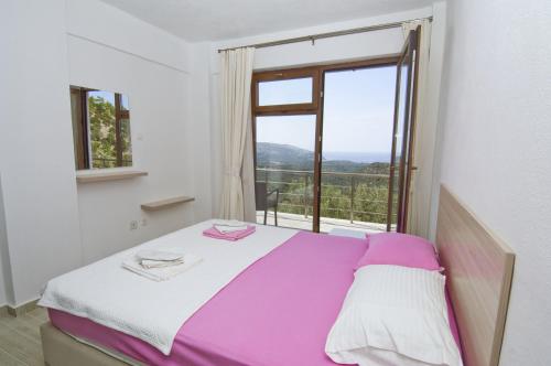 - une chambre avec un lit et une grande fenêtre dans l'établissement Evim Zeytinlik Pension, à Gülpınar