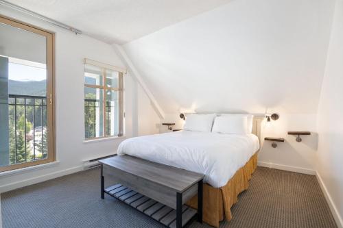 a white bedroom with a bed and a window at Whistler Village Centre by LaTour Hotels and Resorts in Whistler