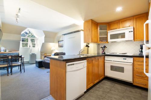a kitchen with wooden cabinets and white appliances at Whistler Village Centre by LaTour Hotels and Resorts in Whistler