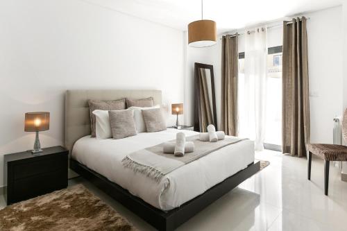 a white bedroom with a large bed with two pillows at Caminho da Praia in Ferrel