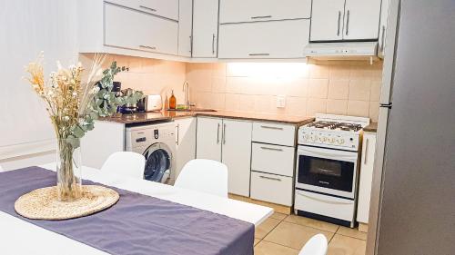una cocina con armarios blancos y una mesa con jarrón en Casa Huesped Mendoza Modernismo y confort en este hermoso apartamento !! en Mendoza