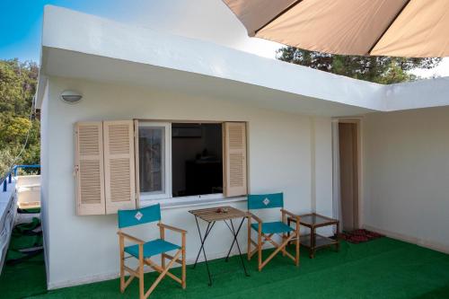 een patio met stoelen, een tafel en een raam bij Anni's cozy apartments 50m from the beach in Agia Triada