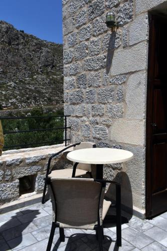 a white table and chairs sitting next to a stone wall at Akroyiali Apartments in Gerolimenas