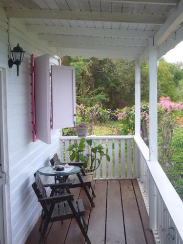a porch with two chairs and a table on it at Green Roof Inn in Carriacou