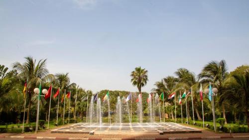 a fountain with flags in a park with palm trees at GRANADA l'Amitié in Bamako