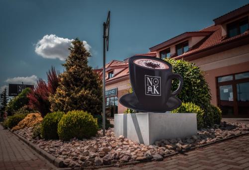 a large coffee cup statue in front of a building at Hotel Novy Kastiel - Self check-in in Topoľčany
