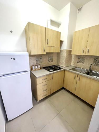 a kitchen with wooden cabinets and a white refrigerator at Le Stanze di Lucia vicino Ospedale Cardinale Panico a Tricase in Tricase
