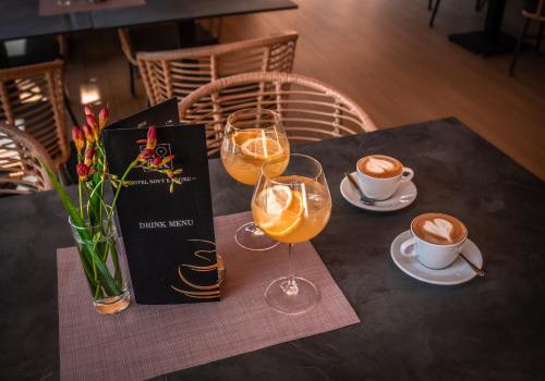 a table with two glasses and a book and cups of coffee at Hotel Novy Kastiel - Self check-in in Topoľčany