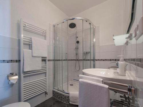 uma casa de banho branca com um chuveiro e um lavatório. em B&B Mediterran Nassau em Nassau