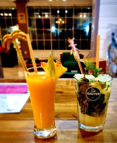 two drinks are sitting on a wooden table at Hotel Des Neiges in Cilaos