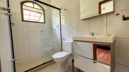 La salle de bains est pourvue de toilettes, d'un lavabo et d'une douche. dans l'établissement Residencial Canto Livre Apart Hotel, à Penedo