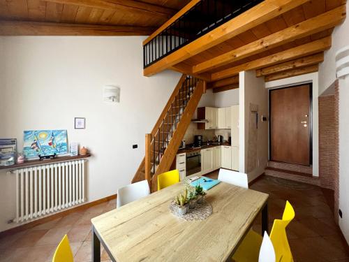 kuchnia i jadalnia z drewnianym stołem i żółtymi krzesłami w obiekcie Casa Cele w mieście Garda