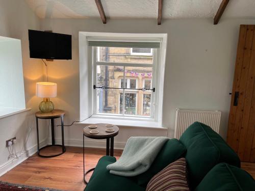 a living room with a green couch and a window at Little Withens in Haworth