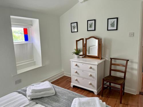 a bedroom with a dresser and a mirror and a chair at Little Withens in Haworth