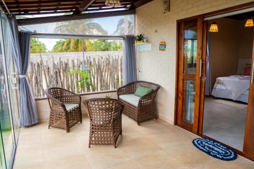 een kamer met een terras met stoelen en een bed bij Beira-mar Chalé Maceió - Camocim in Maceió