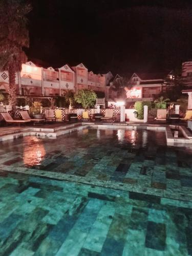 a swimming pool at night with buildings in the background at Hotel Des Neiges in Cilaos