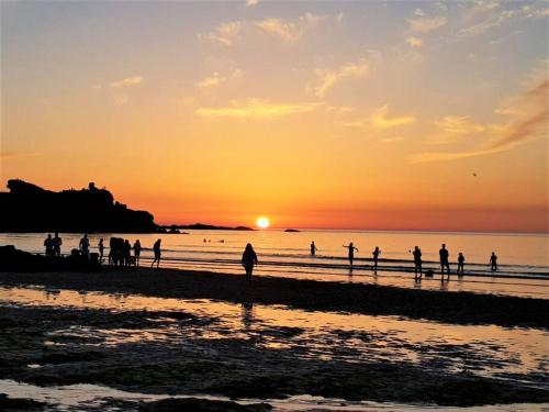 a group of people walking on the beach at sunset at High quality detached house with parking St. Ives in St Ives