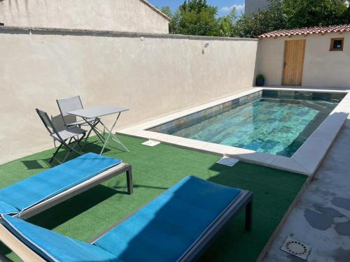 a swimming pool with two chairs and a table and a table and a tablektop at Villa Jasmin in Carpentras