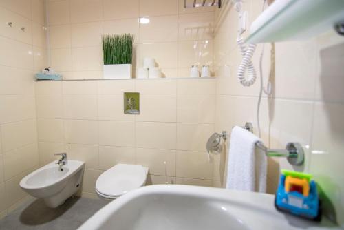 a white bathroom with a toilet and a sink at Velence Sunset Wellness Apartman in Velence