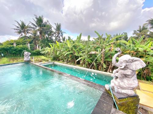 an elephant statue sitting next to a swimming pool at Ubud Rice Field House in Ubud