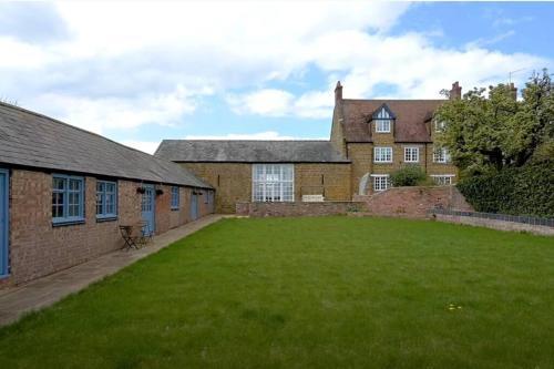 a large yard in front of a brick building at Beautiful 2 bed cottage picturesque tranquil setting in Sywell