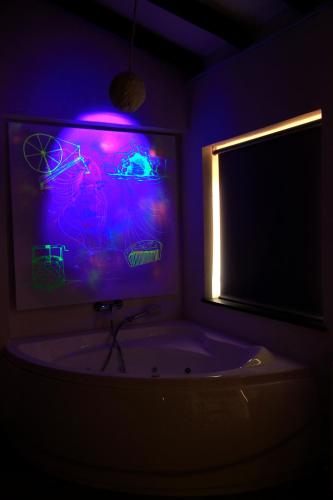a bathroom with a tub and a tv with purple lights at La Posada de la Xana in Llanuces