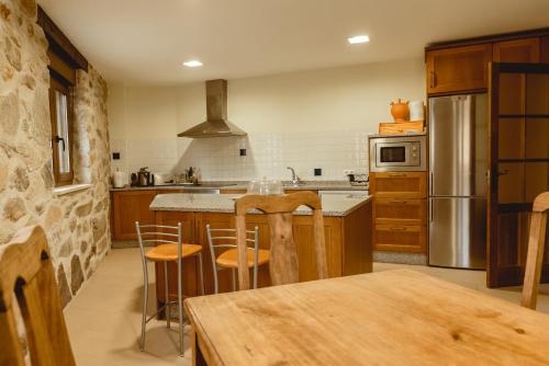 a kitchen with wooden cabinets and a kitchen island with bar stools at La pata del buey in Navamorisca