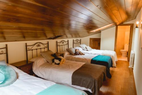 um quarto com 3 camas e um tecto de madeira em La pata del buey em Navamorisca