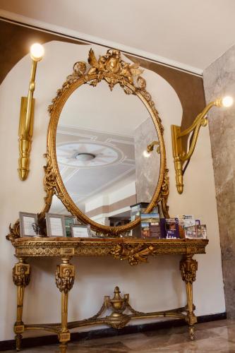 an ornate gold mirror on a table in a room at Art Hotel Pandos in Tabiano