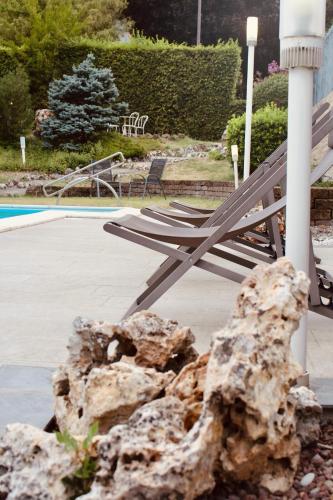 a bench next to a rock next to a pool at Art Hotel Pandos in Tabiano