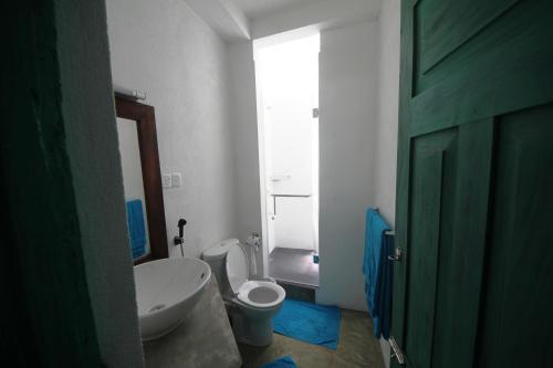 a bathroom with a white toilet and a sink at Hikks Villa in Hikkaduwa