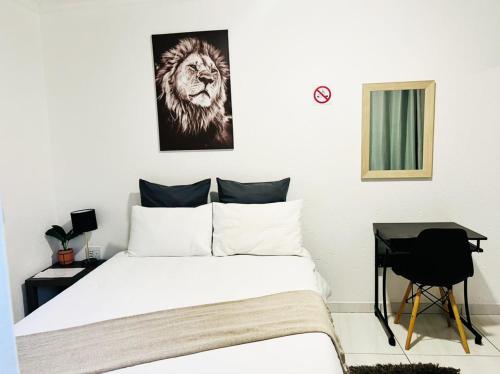 a bedroom with a bed with a lion picture on the wall at Zindiza Guesthouse in eMalahleni
