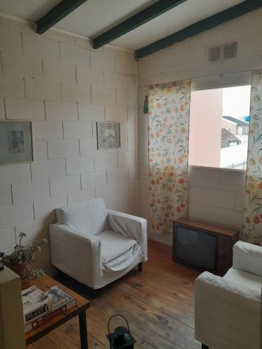 een woonkamer met een witte stoel en een tv bij Parivaar Host in Concepción del Uruguay