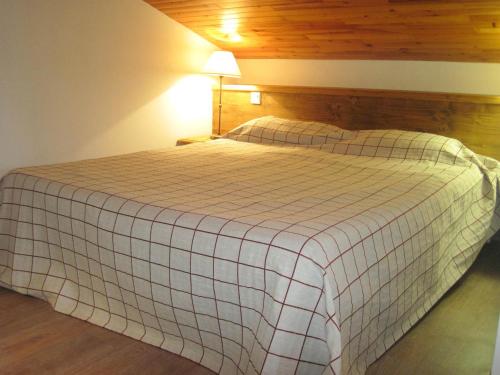 une chambre avec un lit avec une couverture à carreaux dans l'établissement Studio Duplex Rénové · Proche Pistes et Commerces · Balcon - FR-1-181-2466, à La Plagne Tarentaise