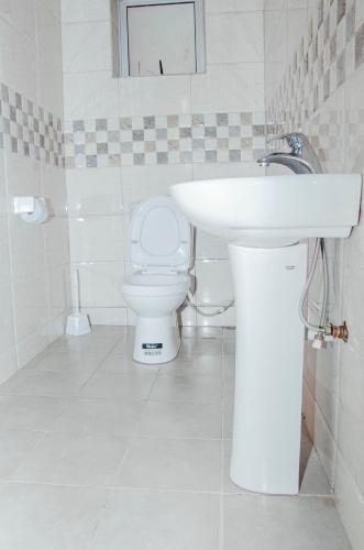 a white bathroom with a sink and a toilet at Hotel Santa Maria in Arua