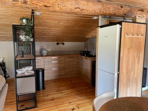 Il comprend une cuisine avec un réfrigérateur blanc et des plafonds en bois. dans l'établissement Sublime studio de caractère ,50 m2 climatisé ., à Montlaur-en-Diois