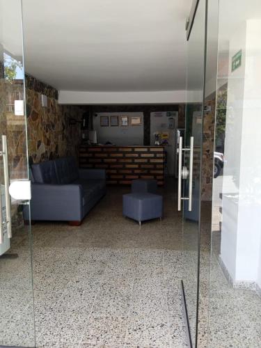 a living room with a couch and a glass wall at Hotel Urbano 70 in Medellín