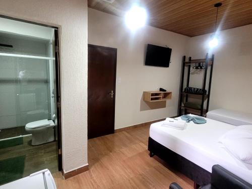 a bedroom with a bed and a bathroom with a toilet at Hotel Serra do Mar in Paranaguá