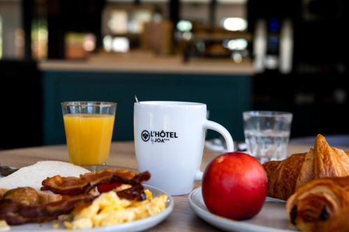 a table with breakfast foods and a cup of orange juice at L'hôtel by JOA de Saint-Paul-Lès-Dax in Saint-Paul-lès-Dax
