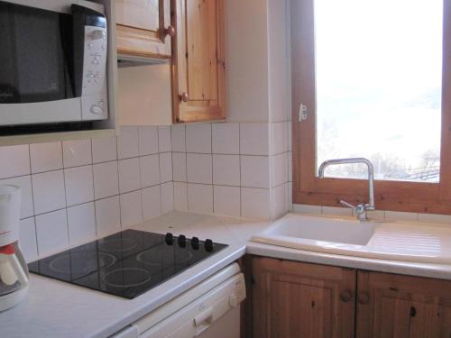 une cuisine avec une cuisinière, un évier et un micro-ondes dans l'établissement Appartement Duplex Spacieux · Proche Pistes · 8 pers · Vue Mont-Blanc - FR-1-181-2488, à La Plagne Tarentaise