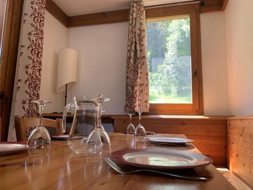- une table avec des verres à vin sur une table en bois avec une fenêtre dans l'établissement Studio cosy à deux pas des pistes avec balcon et casier à skis - FR-1-181-2482, à La Plagne Tarentaise