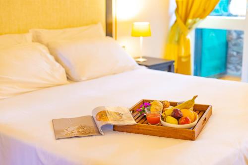 a tray with a tray of fruit on a bed at UNAHOTELS Club Hotel Ancora in Stintino