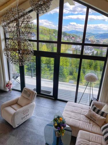 a living room with a couch and a large window at be be Chalet - premium jacuzi & private pool in Bukovel